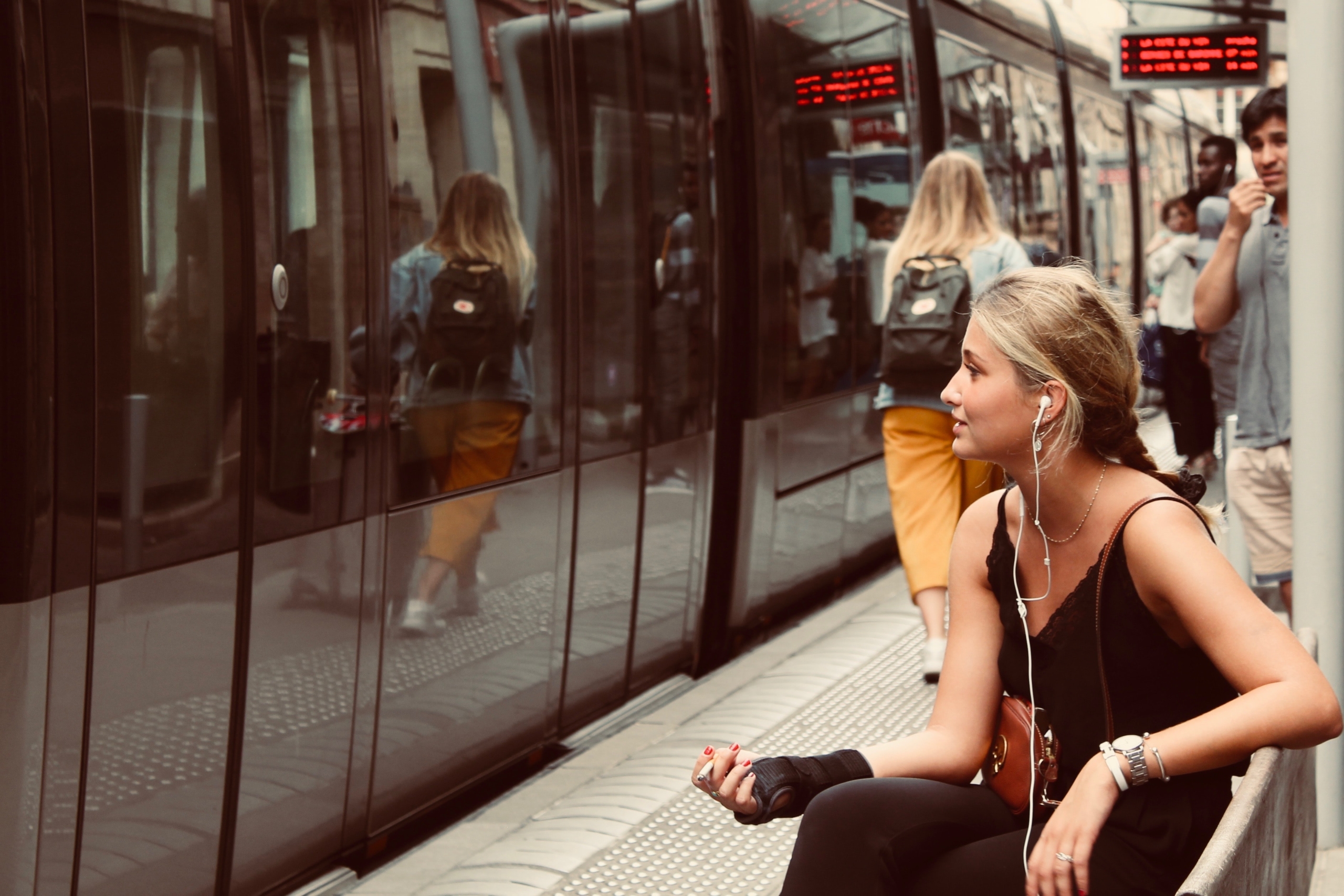 地下鉄でイヤホンをして座っている女性の画像